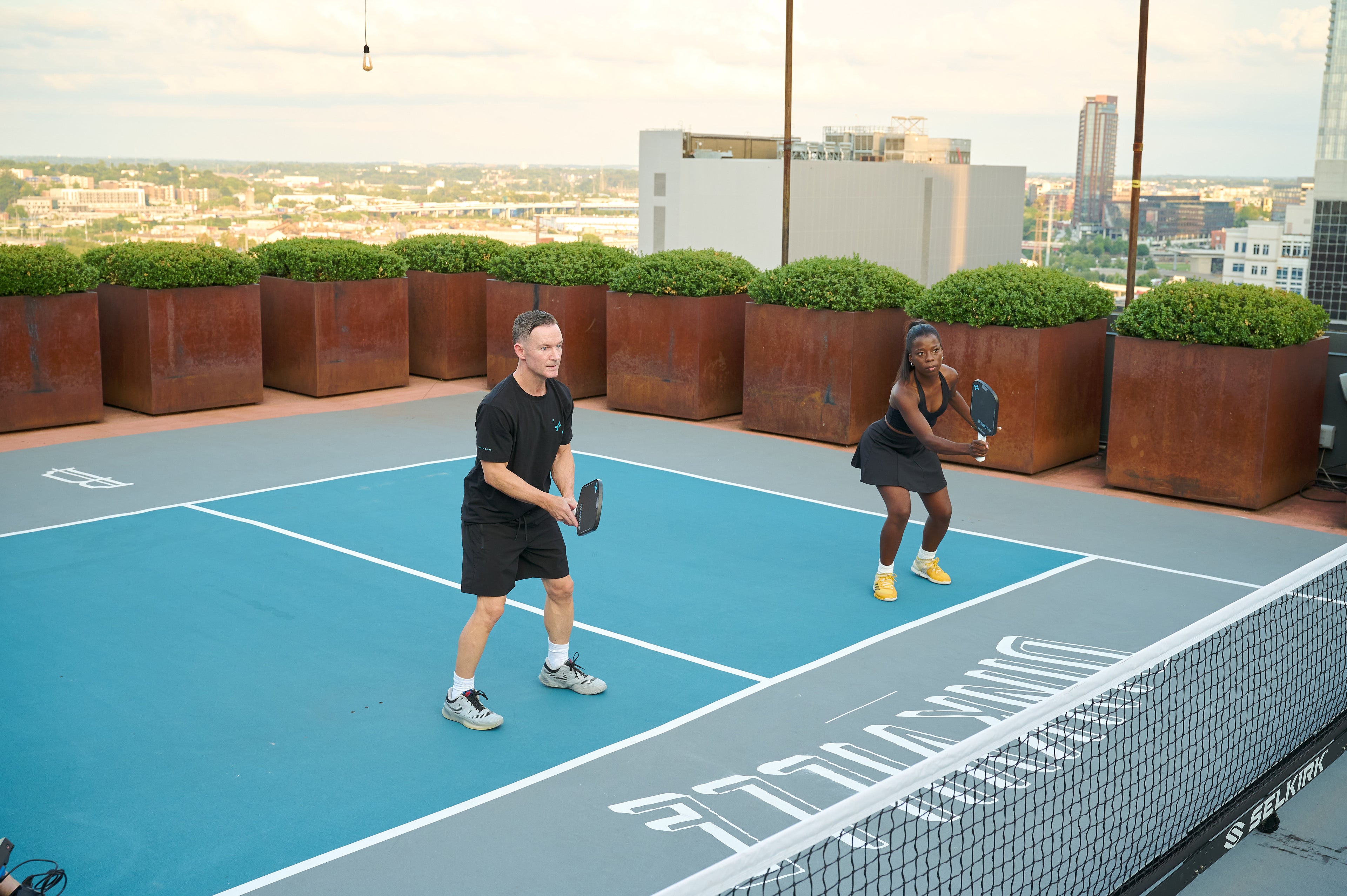 Two people playing pickleball on an outdoor court with a cityscape in the background using F+B Carbon Fiber
Pickleball Paddles