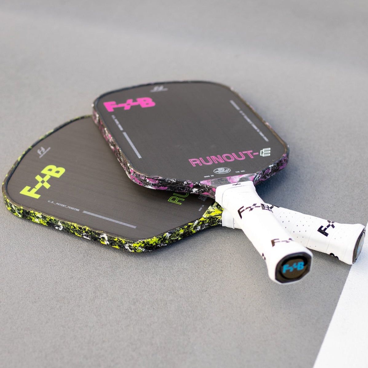 Two pickleball paddles with 'F+B' branding on a gray surface.